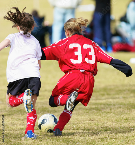two youth girls fight for the soccer ball during a game