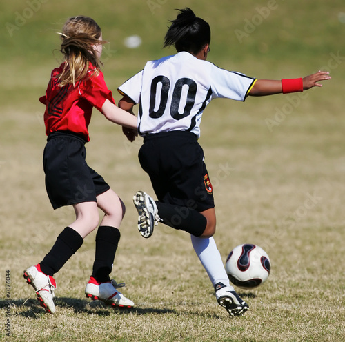 Two youth soccer girls compete for the ball