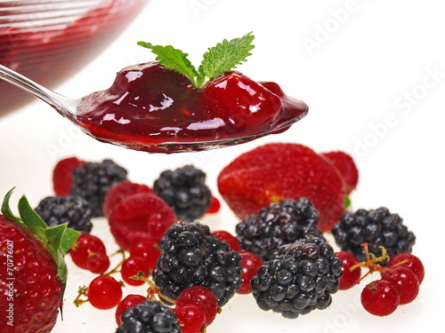 rote Grütze auf einem Löffel, auf einer Schüssel und frischen Beeren auf weißem Hintergrund