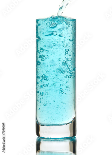 Blue drink being poured into a glass, isolated on white