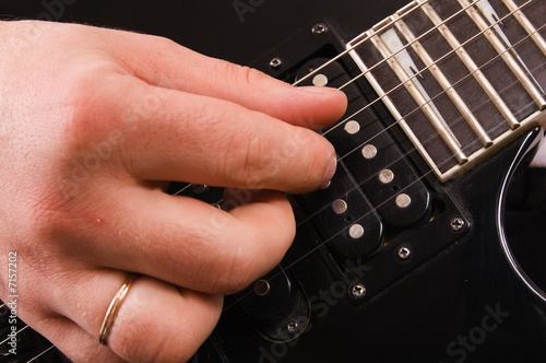 The man plays a close up of a hand on an electroguitar photo