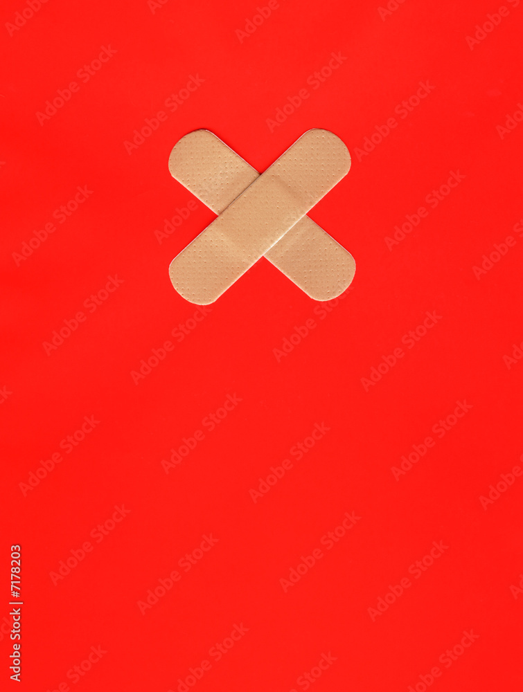 Two plasters forming a cross on red background Two plasters forming a cross on red background