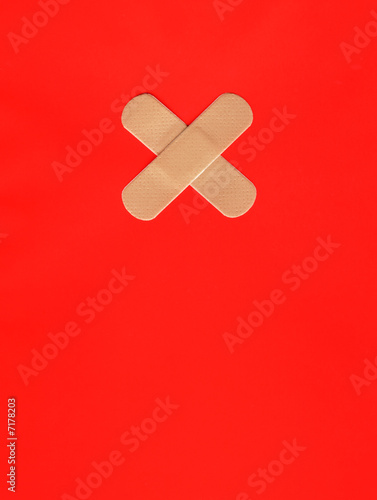 Two plasters forming a cross on red background