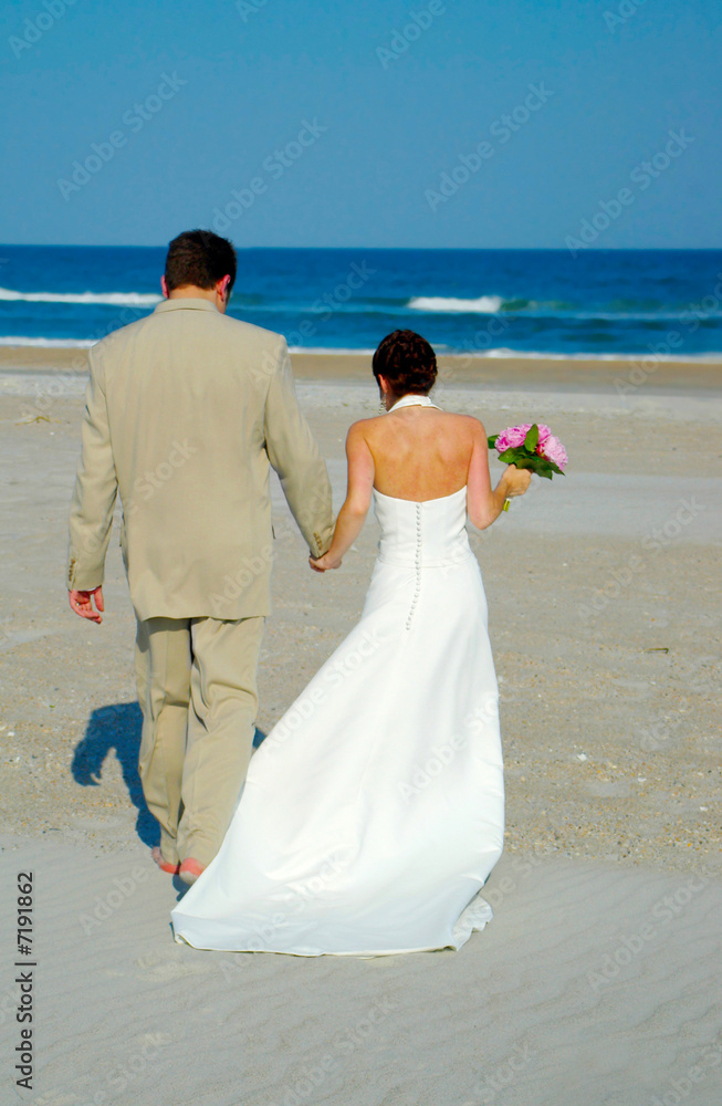 Young wedding couple walking on the beach