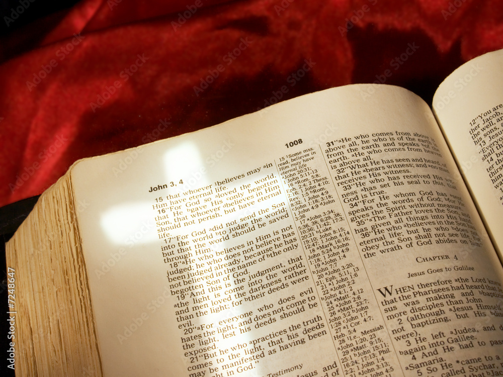 Fototapeta premium Cross of light over John 3:16 in open Bible