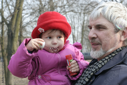 Granddaughter with grandfather released soap bubbles photo