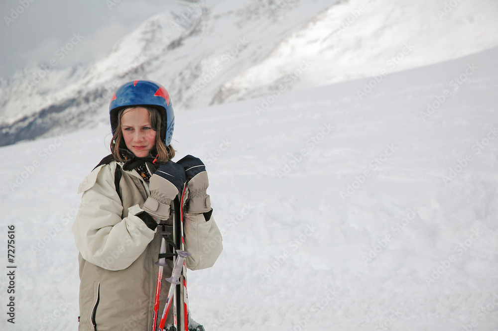 portrait of girl in snowy mountains holding skis