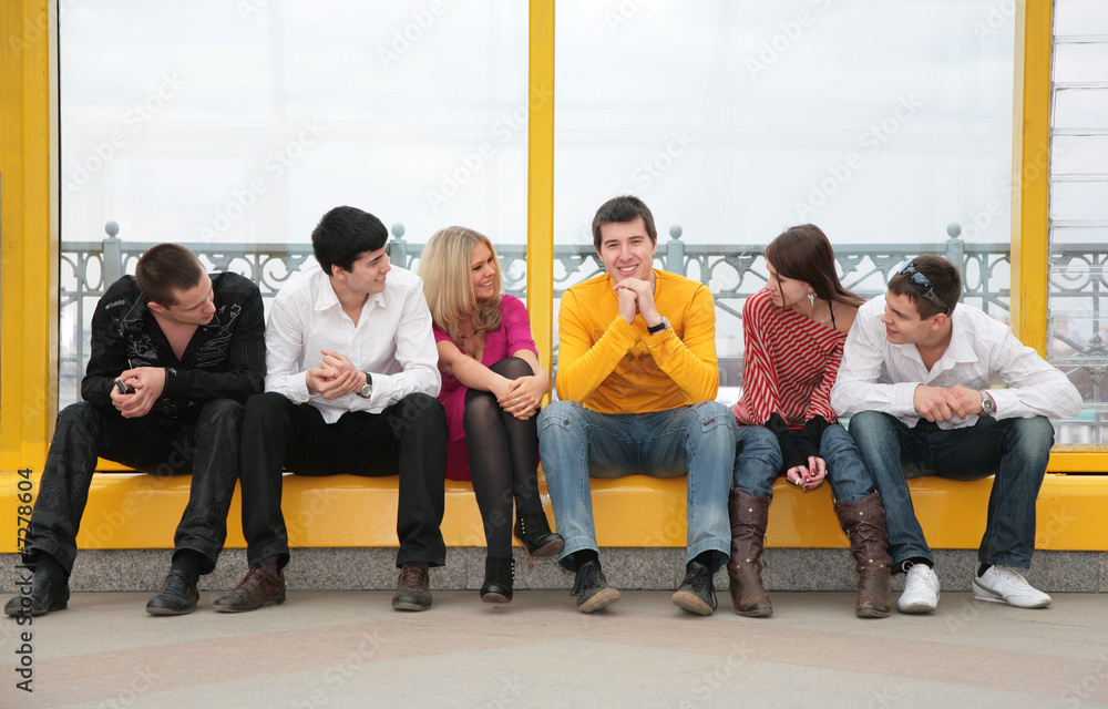group of young people sit on footbridge