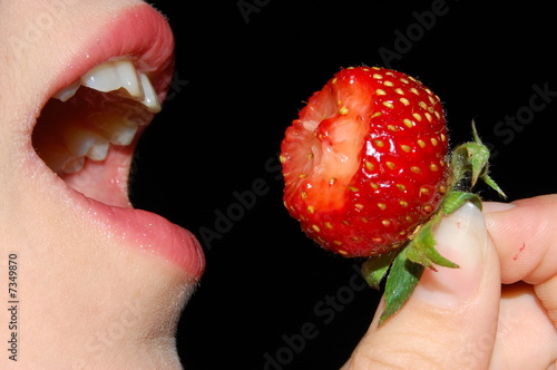The girl eats a strawberry