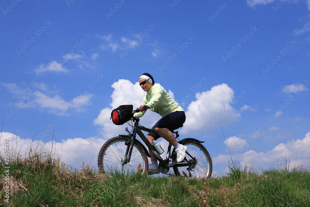 Young lady cycling, blue sky background