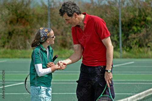father and daughter shaking hands after tennis match