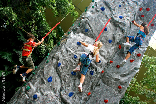 Young children doing rock climbing in an indoor sports center.