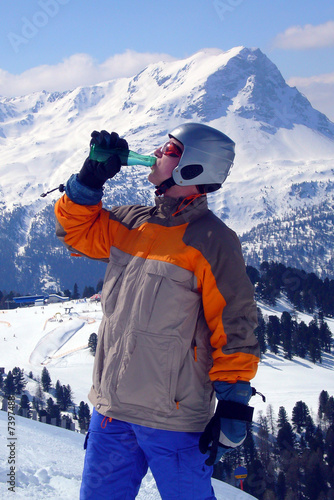 Snowboarder drinking mineral water before riding down.