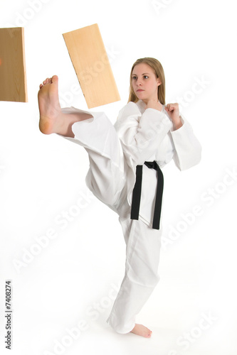 Black belt female martial artist doing board break.
