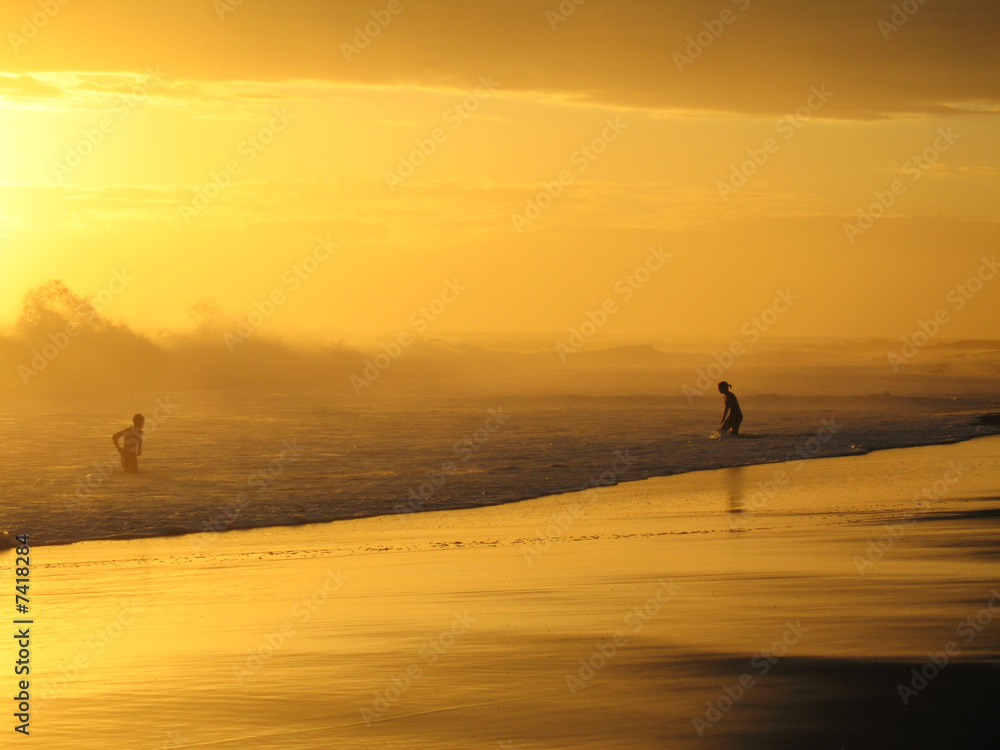 couple jouant dans les vagues au coucher du soleil