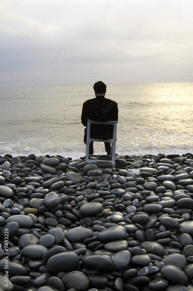 Silhouette of businessman meditating on the beach