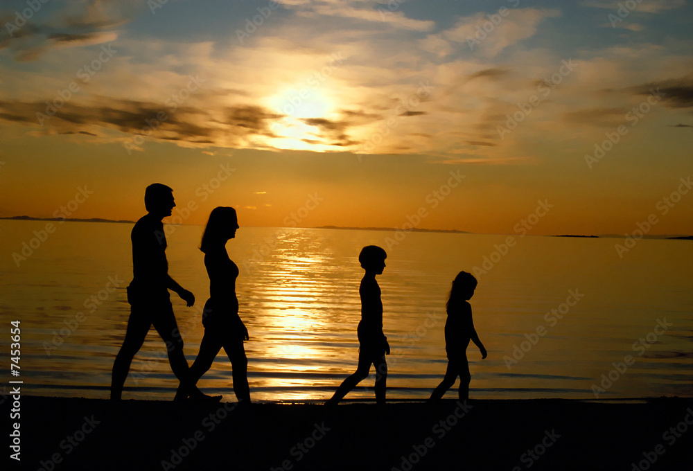 Family Strolling On Beach At Sunset
