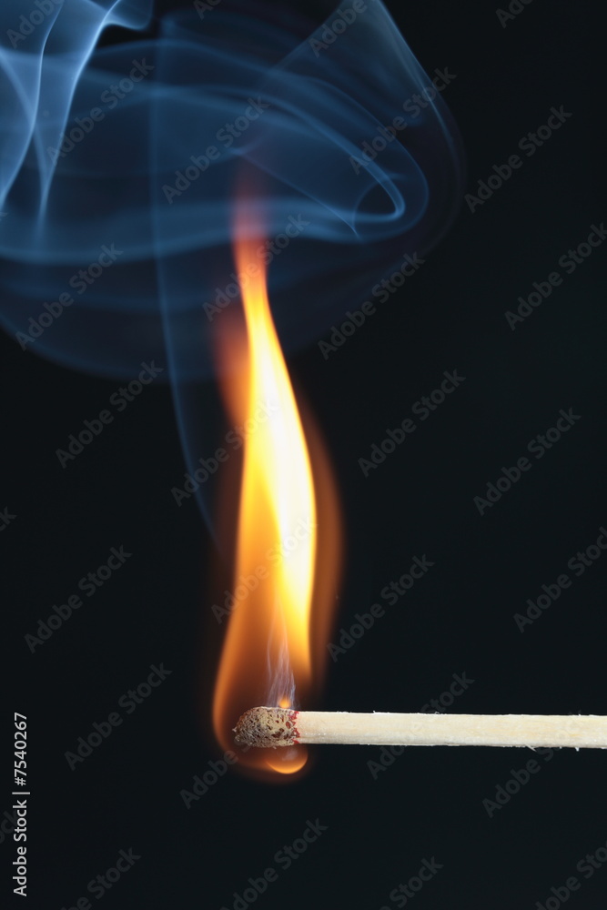 ignited match with blue smoke on black background