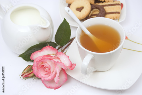 Tea cup with cookies, milk and a rose