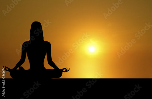 front silhouette of woman meditating on sunset background