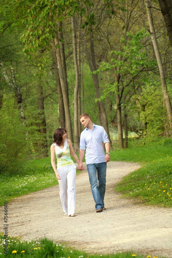 young and happy couple taking a walk in a park young and happy couple taking a walk in a park