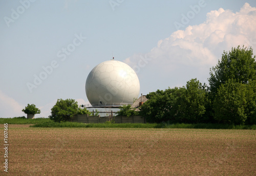 A landscape with an army radar and a field in the front