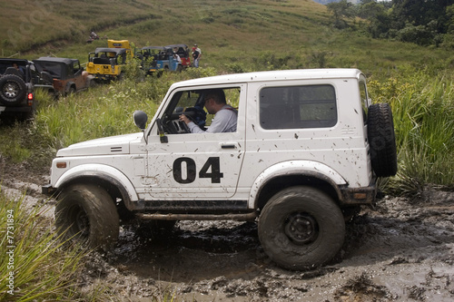 A white jeep splattered and caked with mud © Herjua