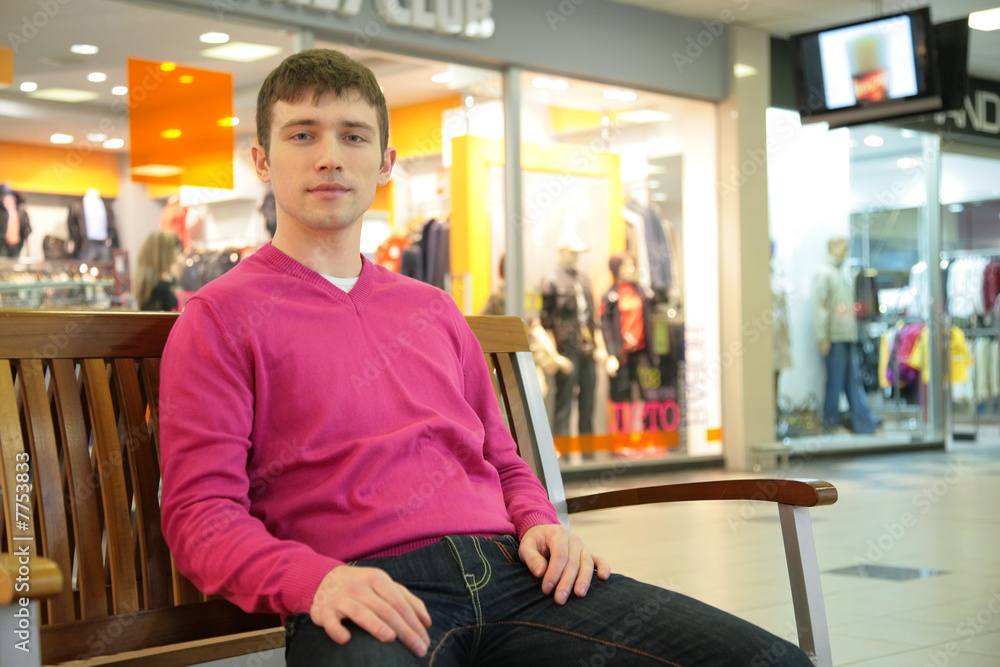 Fototapeta premium young man sits on bench in mall