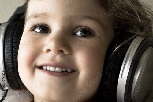 Smiling little girl with headphones listening to music