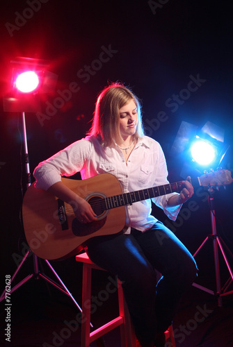 Teenage girl with guitar and stage lights