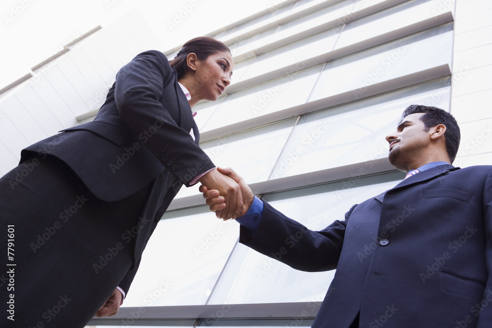 Two business people shaking hands outside office