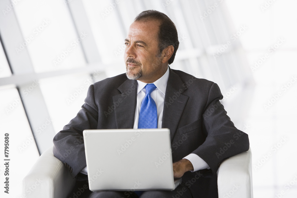 Businessman using laptop in lobby Businessman using laptop in lobby