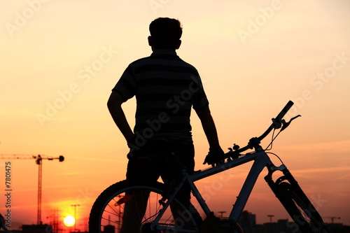 Biker resting against sunset