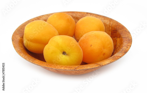 Apricots in wooden dish isolated on white background