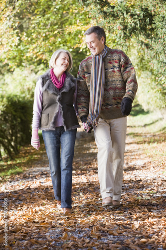 Senior couple walking along autumn path