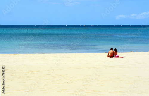 Romantic couple sitting on the sandy beach in the vacation