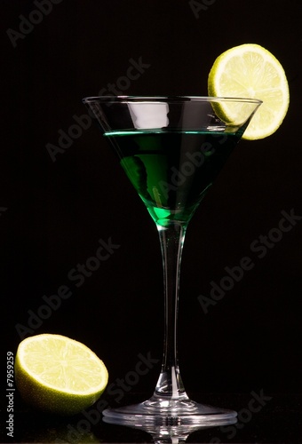 Green cocktail with green lemon on black background