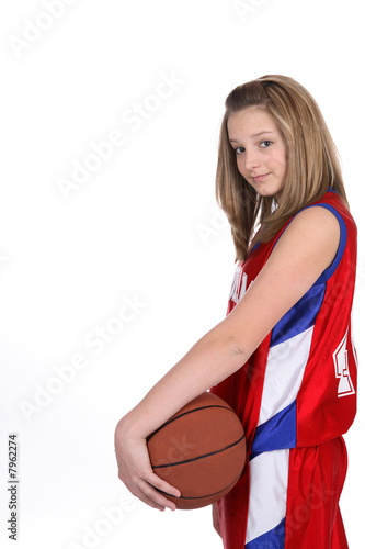 Pretty teenage girl in sports uniform holding the basketball.
