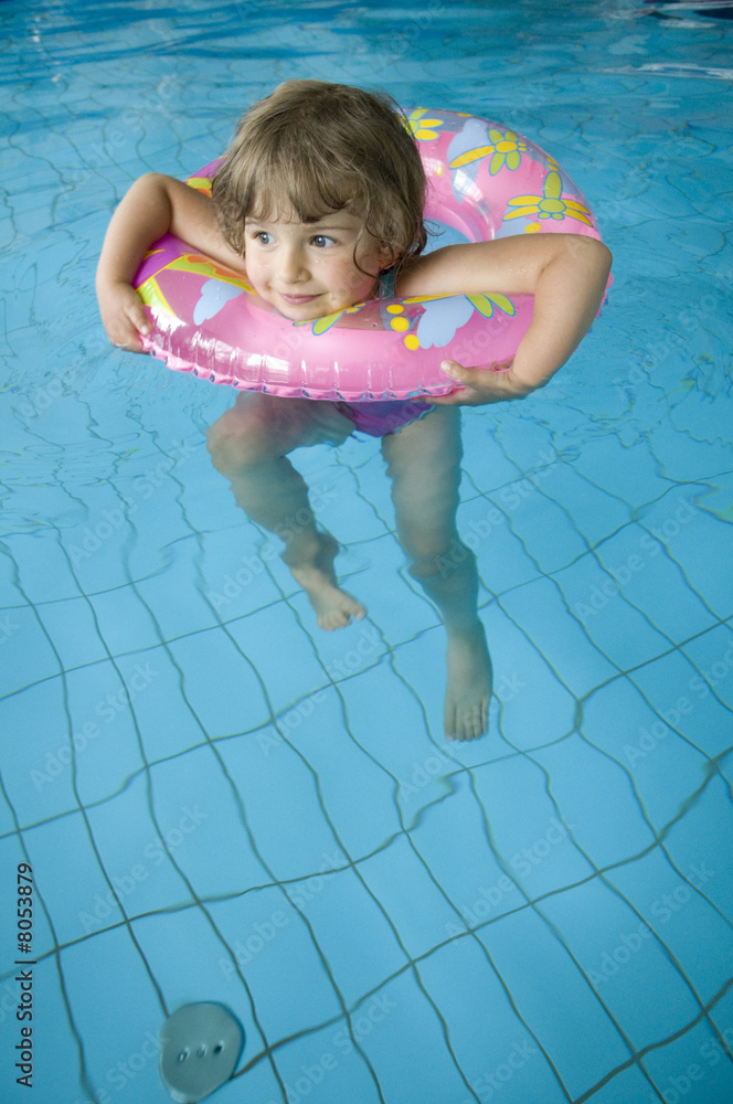 Little girl with inner tube floatig on swimming pool Stock Photo