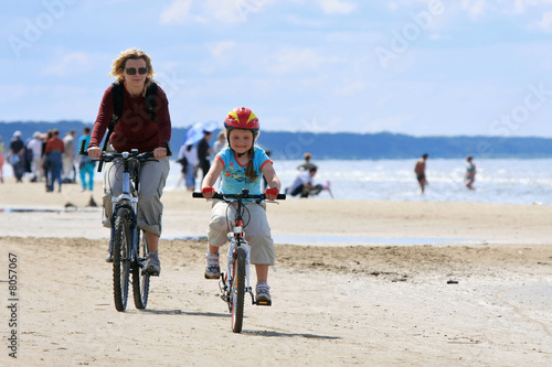 Mother and daughter riding along the beach