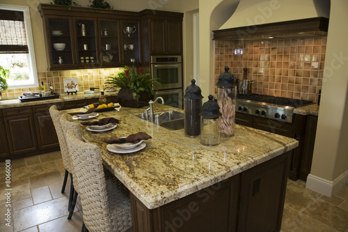 Modern designer kitchen with brown tiles and a granite island.
