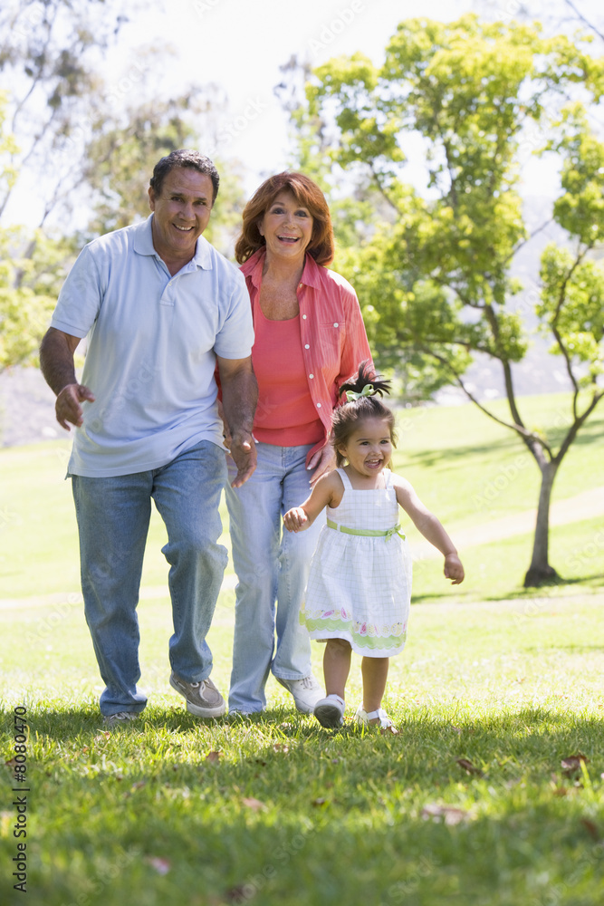 Grandparents walking in park with granddaughter