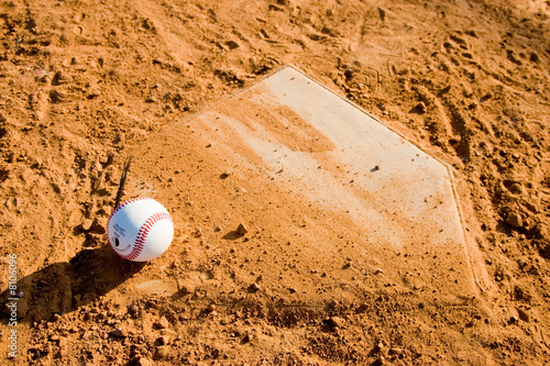 Baseball Sitting on a dirty homeplate.