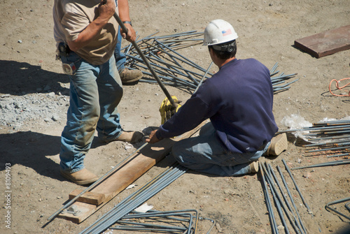 Workers use rebar bender to prepare rods for concrete