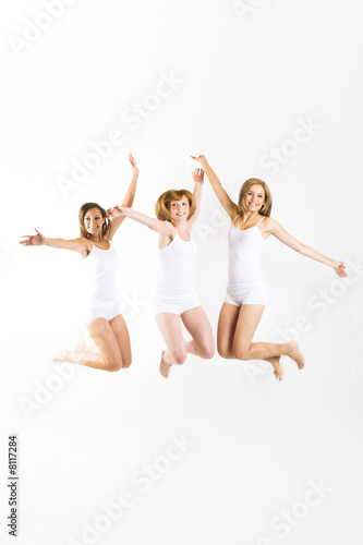 three beautiful smiling women are jumping on white background