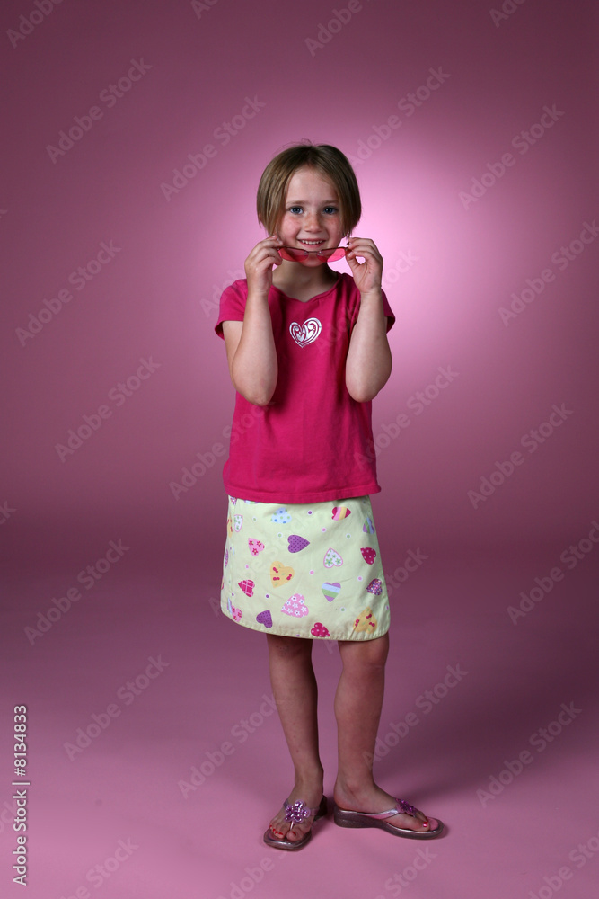 Cute girl in pink removing sunglasses and smiling Cute girl in pink removing sunglasses and smiling