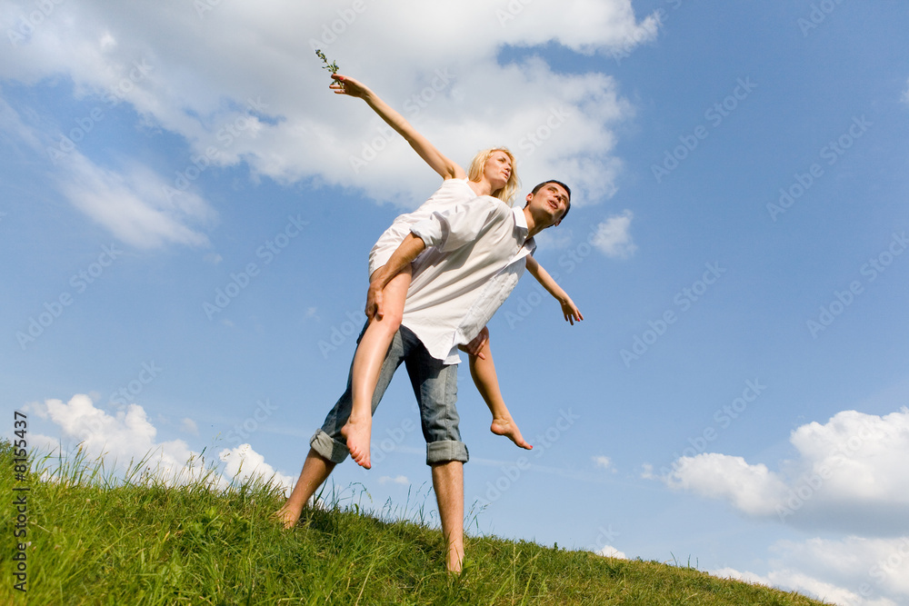 Happy Young Couple - jumping in the sky above a green meadow Happy Young Couple - jumping in the sky above a green meadow