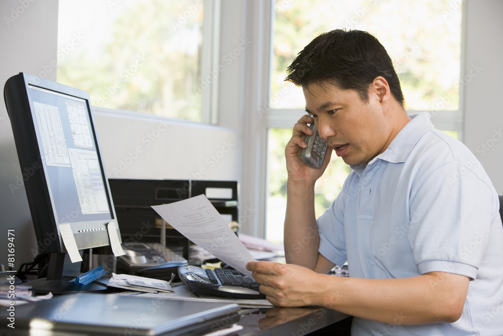 Fototapeta premium Man in home office with computer and paperwork on telephone