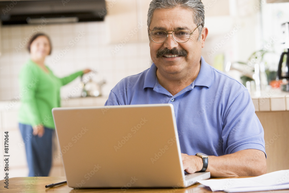 Man in kitchen with laptop smiling Man in kitchen with laptop smiling