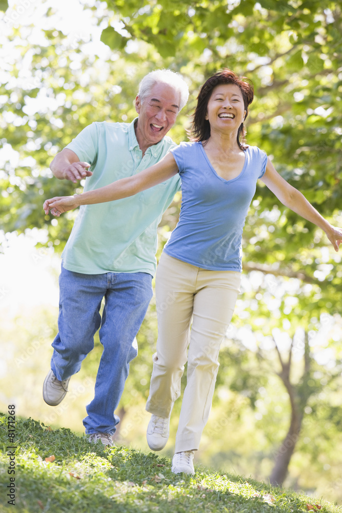 Couple running outdoors in park by lake smiling Couple running outdoors in park by lake smiling